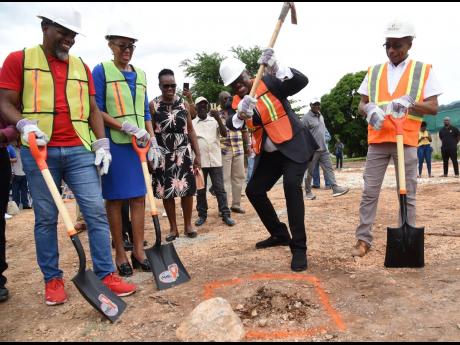 Richard ‘Richie B’ Burgess (2nd right) uses a pick axe to break ground for a four-storey 14-apartment  complex on University Cresent in Papine, St Andrew, valued $600 million. Also breaking ground are Howard Johnson Jr, (left), broker, Howard Johnson R