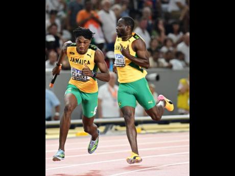 Roshawn Clarke (left) is off and running after collecting the baton from Rusheen McDonald during the men’s 4x400-metre relay final at the 2023 World Athletics Championships in Budapest, Hungary yesterday.