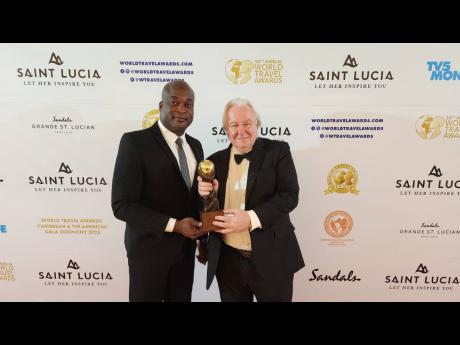 Shane Munroe  (left), CEO, MBJ Airports Ltd, receives the prestigious World Travel Award (WTA) from Graham Cooke, founder of World Travel Awards. Sangster International was again named the Caribbean’s Leading Airport at the WTA event hosted at Sandals Gr