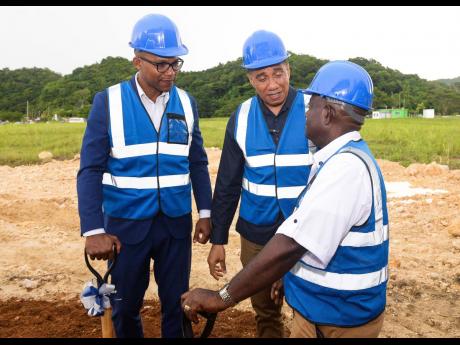 Prime Minister Andrew Holness (centre), converses with National Housing Trust Board member, Doran Dixon (right) following the ground-breaking ceremony for the $907-million Sheffield Palms housing development in Retreat, Westmoreland, earlier this month. Sh