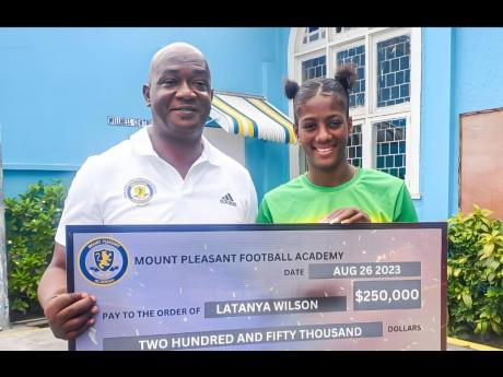 Mount Pleasant Academy general manager Paul Christie (left) hands over a $-250,000 donation to Sunshine Girl Latanya Wilson, who lost almost everything when her home in Kingston was destroyed by fire last Thursday.