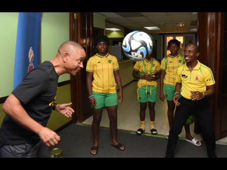 Dennis Chung (left), general secretary of the Jamaica Football Federation heads a ball while Kenneth Richardson, district manager of Sherwin-Williams, looks on.   
