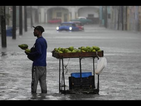An avocado vendor works in a street flooded by rain brought by Hurricane Idalia in Havana, Cuba, early Tuesday, August 29. 