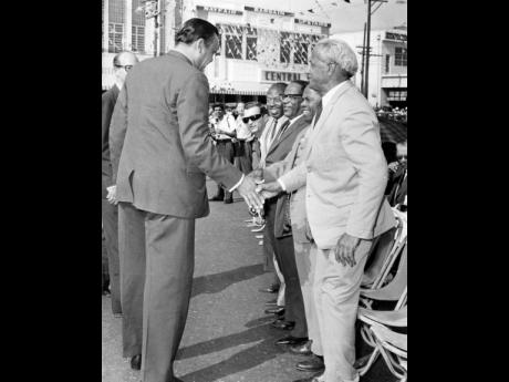 August 1964: Edward Seaga (in dark glasses), minister of development and labour, looks on as Opposition Leader Norman Manley (right) greets the Minister of Housing, Clement Tavares, ahead of a parade.