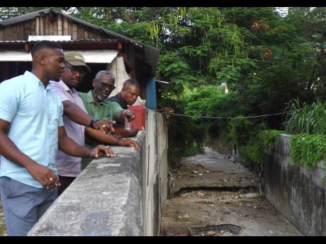 From left: Montego Bay’s Deputy Mayor Richard Vernon; Heroy Clarke, member of parliament for St James Central; and Local Government Minister Desmond McKenzie surveying a section of the Capital Heights gully in the Green Pond community during a tour of se