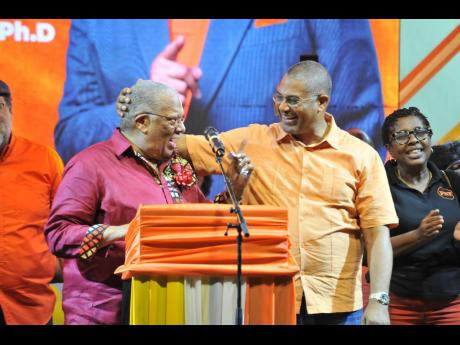 Mikael Phillips (right), member of parliament for Manchester North Western, welcomes his father,  Dr Peter Phillips, former president of the People’s National Party, to the podium at the East Central St Andrew Annual Constituency Conference at Jacisera P