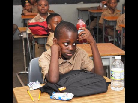 Grade five student Rondre Clarke cools himself down by holding his chilled drink bottle near his head during a class at the Farm Primary and Infant School on Monday, during the first day of the 2023-2024 school year.