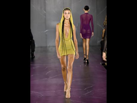  A model wears the chartreuse sheer knit cowl bodycon dress, with the cowl up, partially covering her braids.