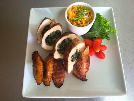Calalloo-stuffed chicken breast is accompanied by macaroni and cheese, fried plantain and vegetables.