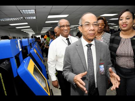 Dr Horace Chang (second left), deputy prime minister and minister of national security (MNS), speaks to the media about accessing the online Immigration Customs C5 form during a tour of the Norman Manley International Airport to observe the operations of t