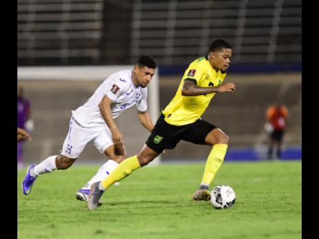 Jamaica’s Leon Bailey (right) moves away from Bryan Acosta of Honduras during a Concacaf World Cup qualifier at the National Stadium on March 22, 2022.  