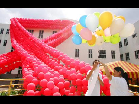 In this file photo university students stand near giant ribbon the international symbol of HIV/AIDS awareness, made from 10,000 balloons during the HIV/AIDS awareness campaign at their campus in Kuala Lumpur.