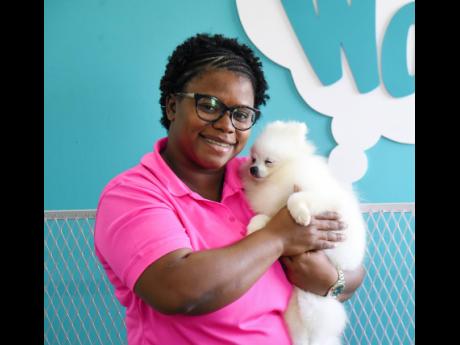 Renee Francis, of Renee’s Palace Pet Resort, cuddles one of the dogs in her care at her Portmore branch yesterday.
