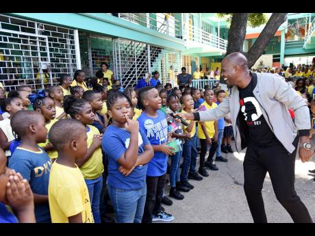 Gospel artiste Marq Johnson (right) gets students at Vaz Prep engaged in singing with him during their Founder’s Day devotion on Friday.