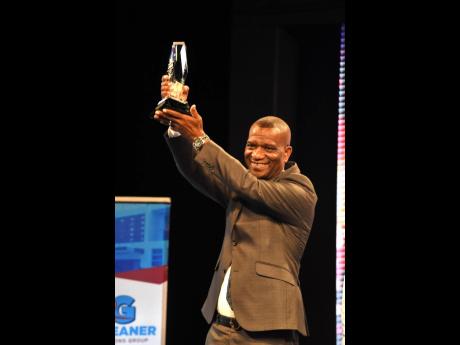 Dr Asburn Pinnock, president of The Mico University, lifts the 2022 RG Platinum Award during the awards ceremony on Tuesday night. The Mico topped a field of seven category awardees for the title in the 43rd RJRGLEANER Honour Awards.