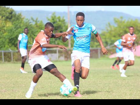 Denbigh High School’s Dusting Cohen (right) is hounded by Central High School’s Nathaniel Howe during their ISSA/Wata daCosta Cup encounter at Effortville yesterday.