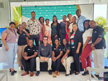 Gerardo De Groot (seated, second left), resort general manager of The Grand Palladium Jamaica Resort and Spa, poses with staff members and the seven scholarship recipients of the Palladium Hotel Group (PHG) scholarship foundation.