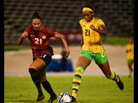 Jamaica’s Cheyna Williams dribbles by Canada’s Jade Rose during the first game of their Olympic qualification tie at the National Stadium on Friday. 