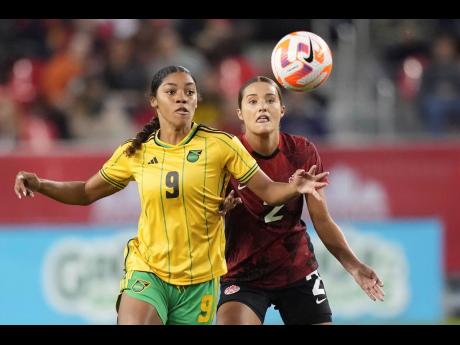 Jamaica’s Kameron Simmonds (left) fights for the ball with Canada’s Sydney Collins during the second leg of a Concacaf Olympic qualification tie in Toronto yesterday.