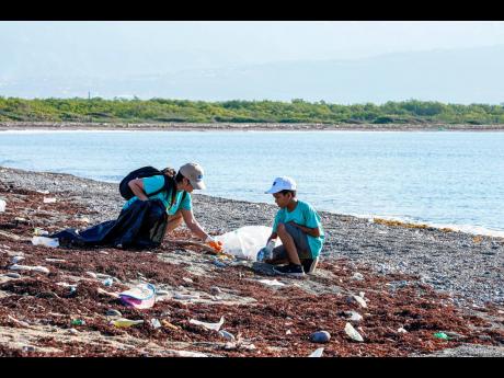 Volunteers, including a child, remove garbage from Port Royal Beach as part of a recent beach clean-up activity hosted by the EU.