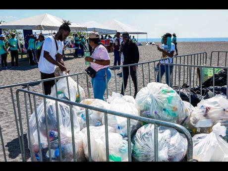 Volunteers secure garbage bags used to collect trash during the beach clean-up activity hosted by the EU in collaboration with the Jamaica Environment Trust at Port Royal Beach.