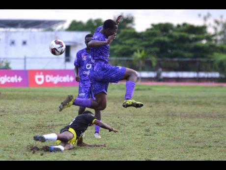 Kingston College’s Oneil Bryan hurdles a tackle from Charlie Smith’s Michael Smith during their ISSA Manning Cup game at Calabar High School yesterday. 