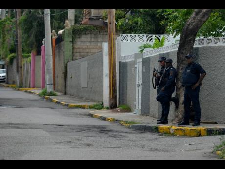 Police personnel keeping a watchful eye on Grants Pen in St Andrew earlier this week as tension remain high after a bloody weekend.