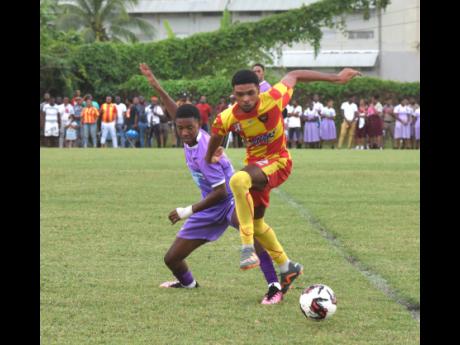 Cornwall College’s Travis Gordon attempts to hurdle a challenge from Irwin High School’s Oneil White during an ISSA/WATA daCosta Cup game at the Irwin High Sports Complex in St James yesterday.