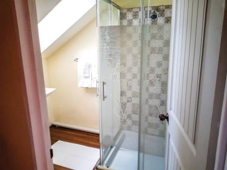  A sloped ceiling bathroom with a glass-enclosed shower.