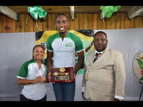 Morant Bay High School alumni Dionne Jackson Miller and Hansle Parchment pose with awards presented to the latter during yesterday’s festivities as Morant Bay Mayor Hubert Williams looks on.