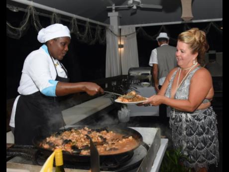 Moya Lewis (left) gives Kimberly Clewis a serving of the seafood creole.
