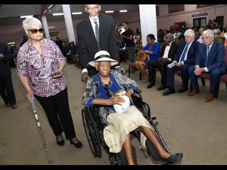 Patsy Hodgson (left) and Owen Currie escorting Sybil Hodgson, mother of Heather Hodgson Moyston, as she carried the urn with her daughter’s remains during the funeral for the late Digicel executive at the Fellowship Tabernacle in Kingston 20 on Thursday.
