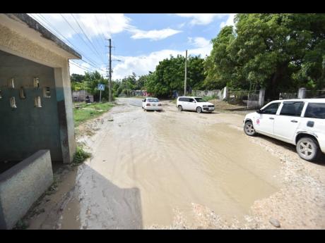 Days after heavy rains fell in the area, the potholes in the Lyssons main road were still filled last Thursday, with a large pool of murky water preventing use of the bus stop. 