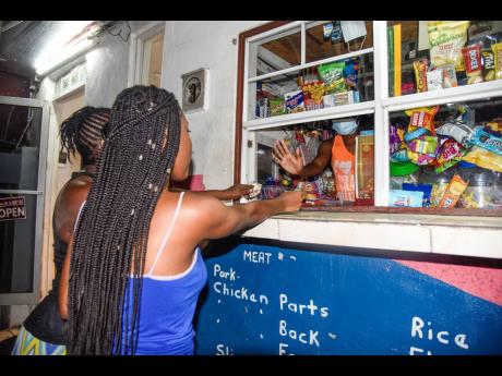 Two women purchase goods at a corner shop in Kingston in Kingston on April 15, 2021.