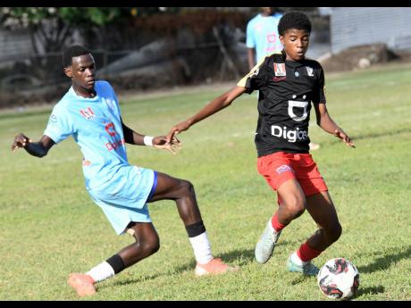 Sean Leighton (right) of Mona High goes past Lavaughn Taylor of St Catherine High during yesterday’s Manning Cup match at  St Catherine High in Spanish Town. Mona won 2-0. 