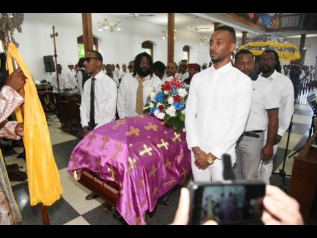 Pallbearers stand guard as the casket of the late Ibo Cooper enters the University Chapel, Mona, on Thursday.