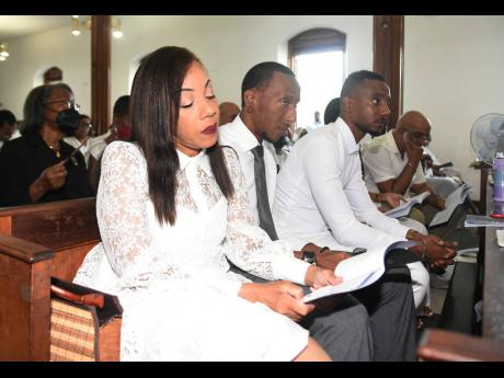  From left, Arianne, Akiri and Abean Cooper sit together during the funeral service for their father Kingsley Michael Mckinson ‘Ibo’ Cooper.
