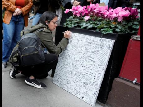 A person signs a message board at a makeshift memorial for Matthew Perry.