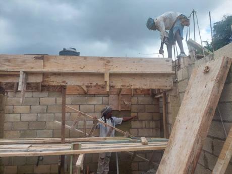 From left: Foreman Audley Dennie and Johnoy Dennie continue working on a two-storey residential structure in Stony Hill, St Andrew, after Monday’s earthquake.