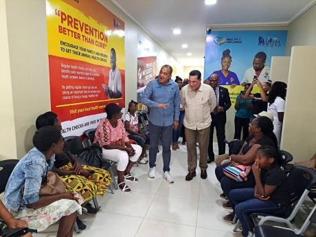 Health Minister Dr Christopher Tufton (centre,left) and St James Southern Member of Parliament Homer Davis (centre, right) greet patients in the waiting area of the Cambridge Health Centre in Cambridge, St James during a tour of the facility on Thursday, N