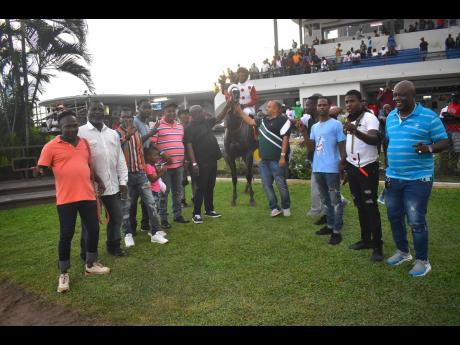 A packed winner’s enclosure turns out to celebrate the Kaz Hoshay Trophy winner, Madelyn’s Sushine and her jockey, leading rider, Reyan Lewis, at Caymanas Park yesterday.