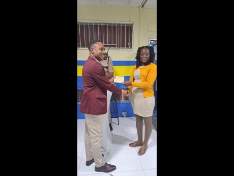 Senior Superintendent of Police Christopher Phillips presents Woman Constable Ronnette Allen with an incentive for being the most outstanding performing officer for the month of October.
