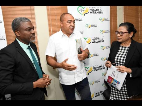 Michael Williams (left), environmental health specialist in the Ministry of Health and Wellness, and Chief Medical Officer Dr Jacquiline Bisasor McKenzie listen as Health and Wellness Minister Dr Christopher Tufton makes a point following a press conferenc