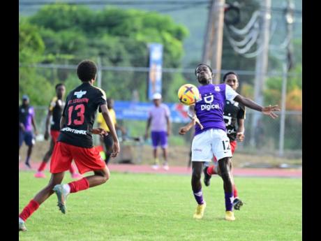 Kingston College’s Kamaul Patterson (centre) controls a pass ahead of Mona High’s Sean Leighton (left) during their Manning Cup match at the Ashenheim Stadium, Jamaica College, on Saturday, November 4, 2023. 