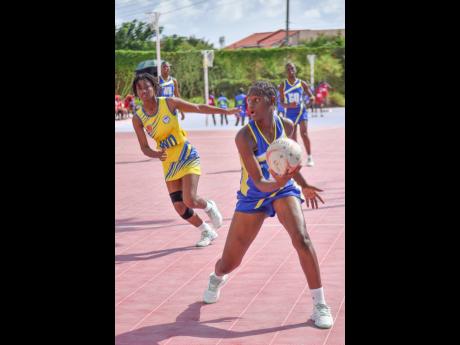 Tisheena Roach (right) of Gaynstead High looks for a teammate before making a pass during yesterday’s ISSA urban schoolgirls senior match against Jose Marti High at  the Leila Robinson Courts. At left is Daunell Wilson of Jose Marti.