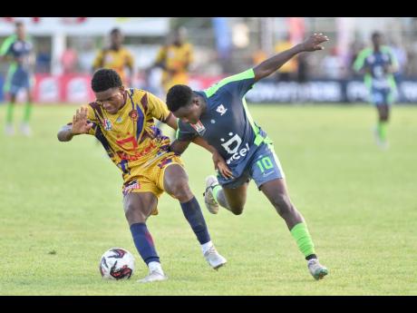Nickoy Gayle (left) of St Andrew Technical tackles Denzel McKenzie of Mona High during their  Manning Cup match at the Anthony Spaulding Sports Complex yesterday.  Mona won 2-0.