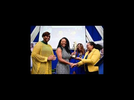 Speaker of the House of Representatives Juliet Holness (left) stands by as Dr Trisha Bailey, author, philanthropist and entrepreneur; receives an award from Geraldon Adams (right), deputy group executive chairperson for the UCC Group of Companies; while Dr
