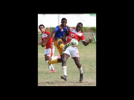 Jonathan Grant High School’s Domonic Grant (centre) boots the ball away from Campion College’s David Thompson (right) during their Walker Cup Knockout football game at Campion College yesterday. Looking on is Campion’s Derek Brandt.  