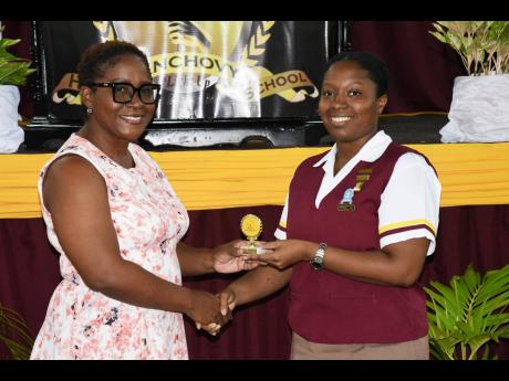Olayinka Salmon (right), a sixth-form student and headgirl at Anchovy High School in St James, was awarded for her outstanding academic achievements in four CAPE subjects, including her elevation to the Principal’s Honour Roll. Here she collects one of h