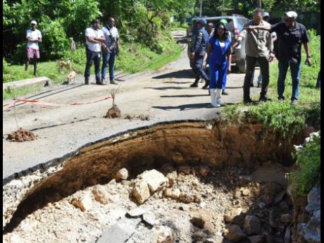 Michael McLeod (right), councillor for the Dalvey division in St Thomas, shows a huge hole in the Cheswick to Dalvey main road to Prime Minister Andrew Holness (centre) and Dr Michelle Charles (left), member of parliament for St Thomas Eastern, during a to